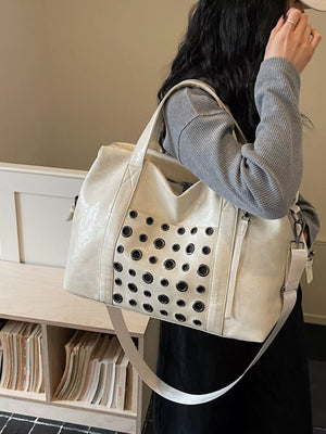 Cream travel organizer bag with eyelet detail and detachable strap.