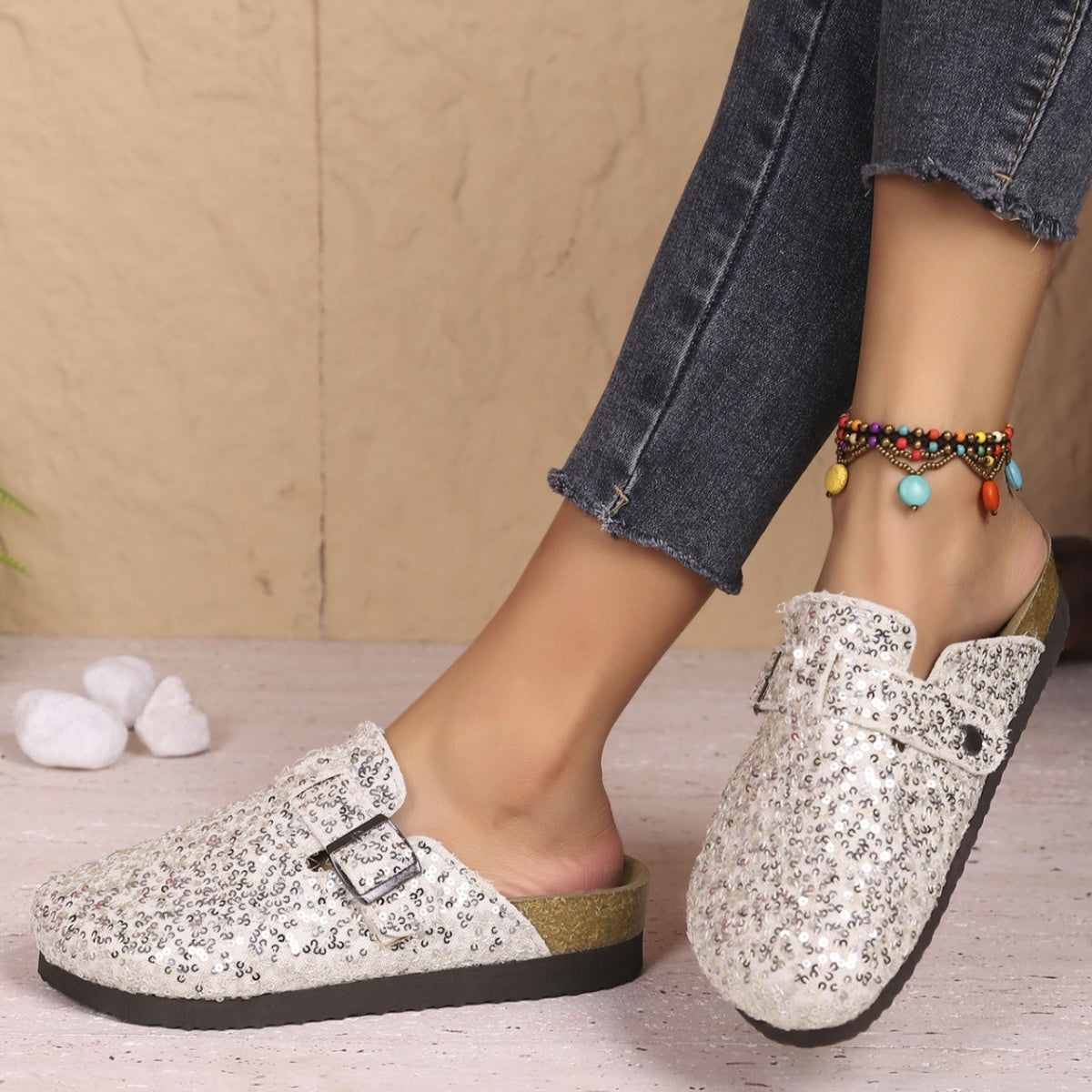 White sequin slip-on mules with decorative buckle detail.
