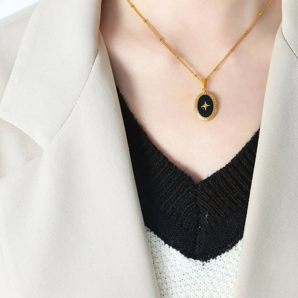 Gold oval pendant necklace with black starburst detail on delicate chain