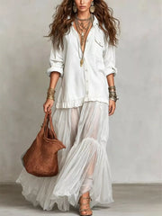 White sheer ruffle maxi dress with buttoned detailing, long sleeves, and tiered skirt.