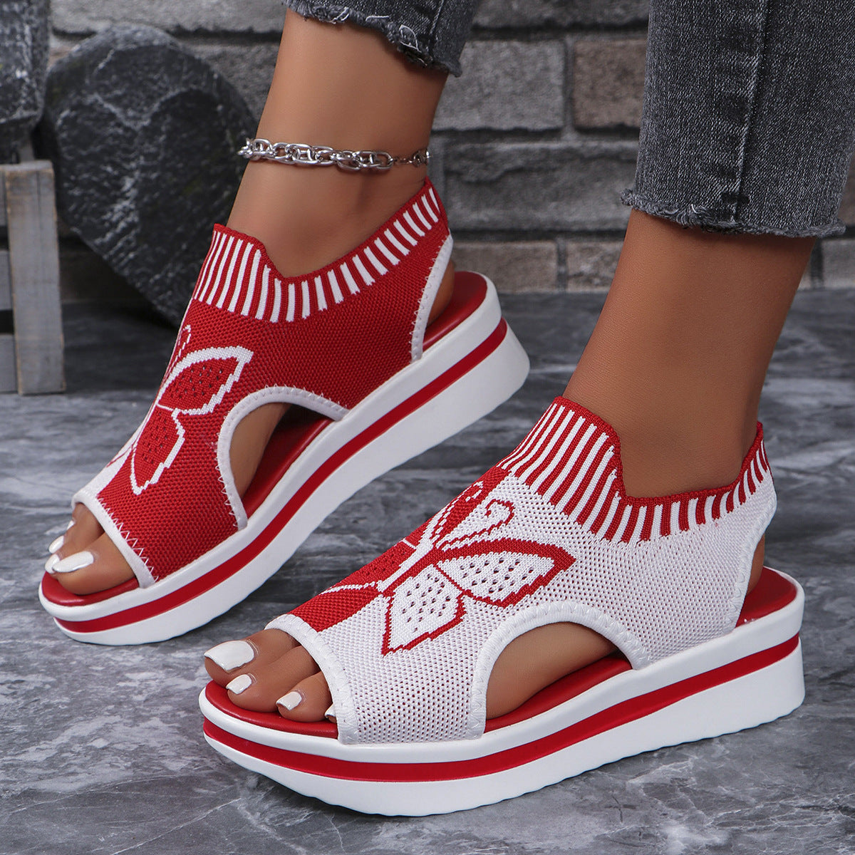 Red and white open-toe wedge sandals with butterfly motif mesh detail and chunky sole.