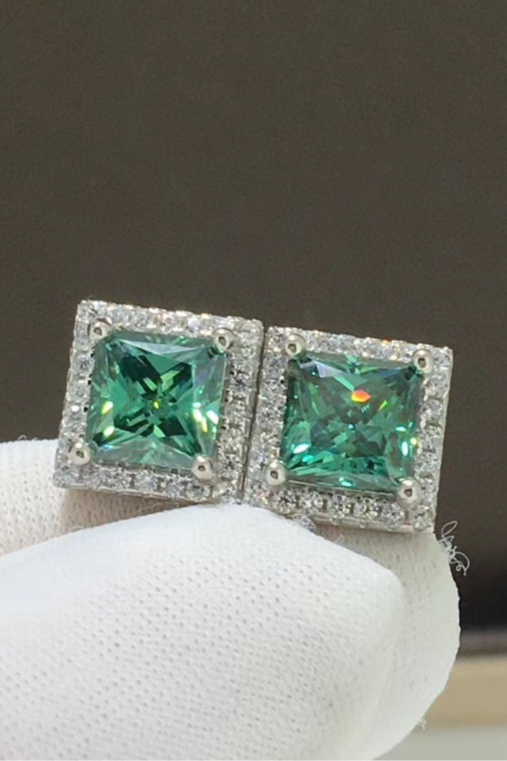 Green square stud earrings with halo of small diamonds.