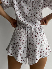 Women's white floral lounge set with relaxed top and flared shorts.