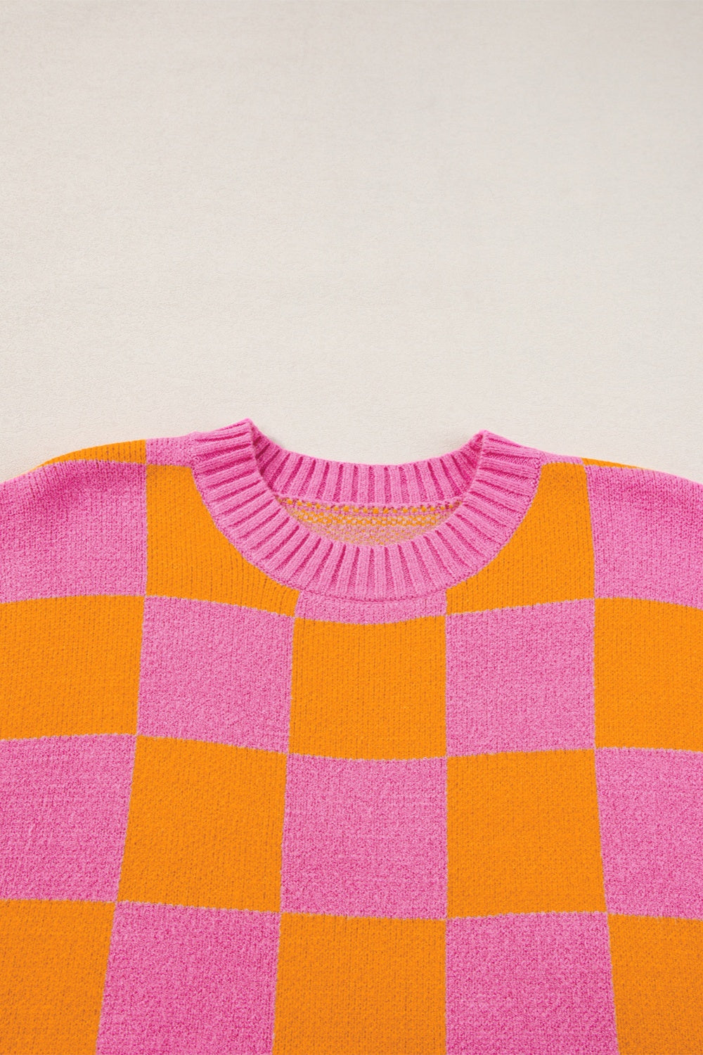 Checkerboard knit sweater in pink and orange with a crew neck and cap sleeves.