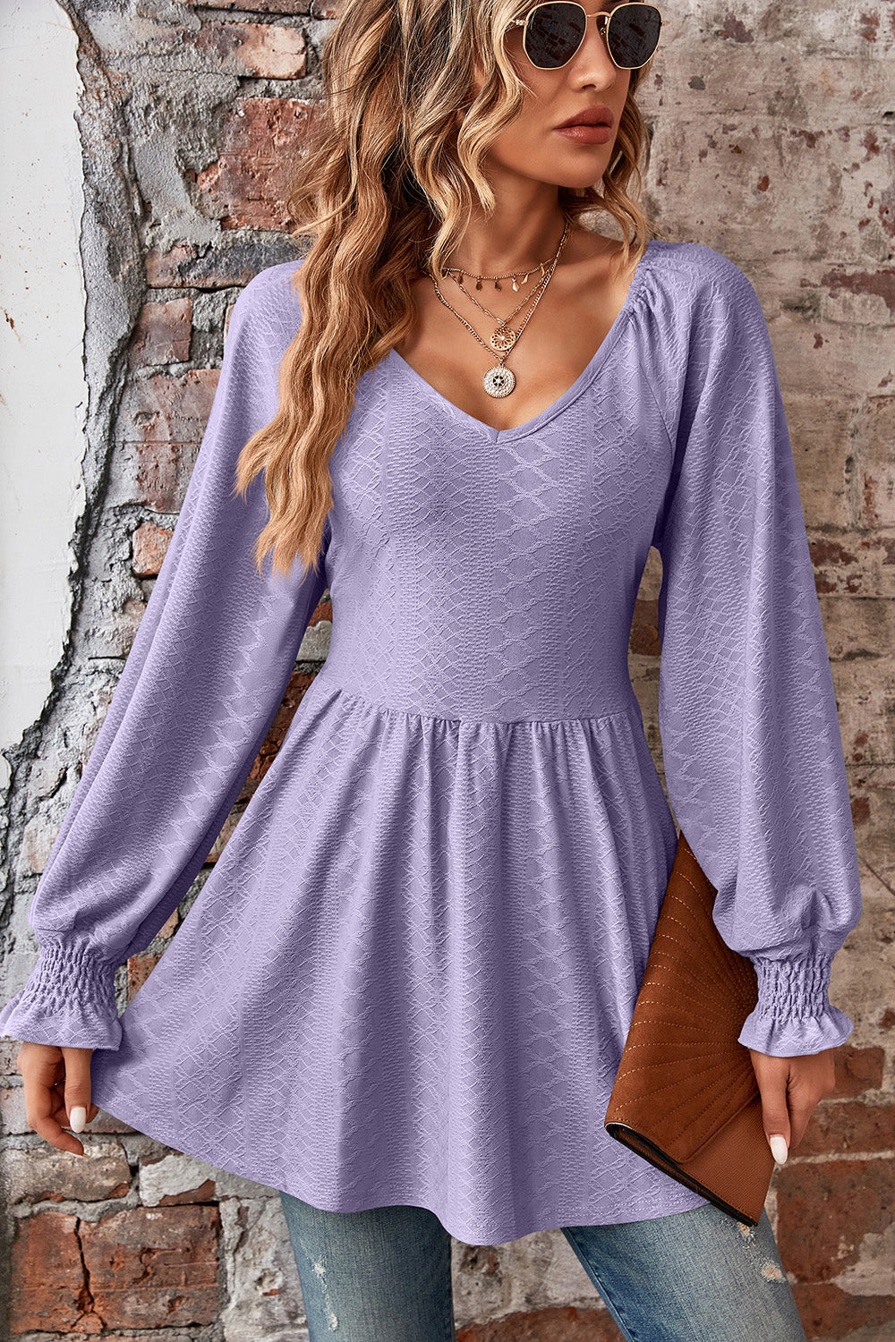 Lilac textured blouse with V-neck, empire waist, and shirred sleeve cuffs.