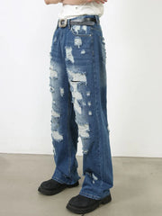 Oversized ripped denim jeans in medium wash with raw edge detail and distressed accents.