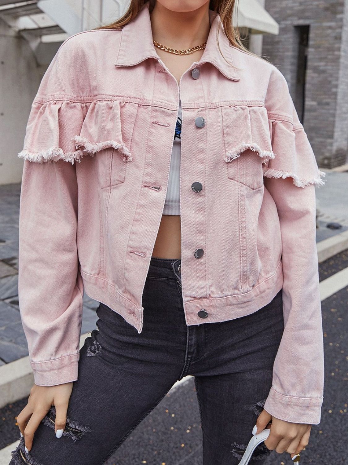 Blush pink denim trucker jacket with frayed ruffle details on the sleeves and chest.