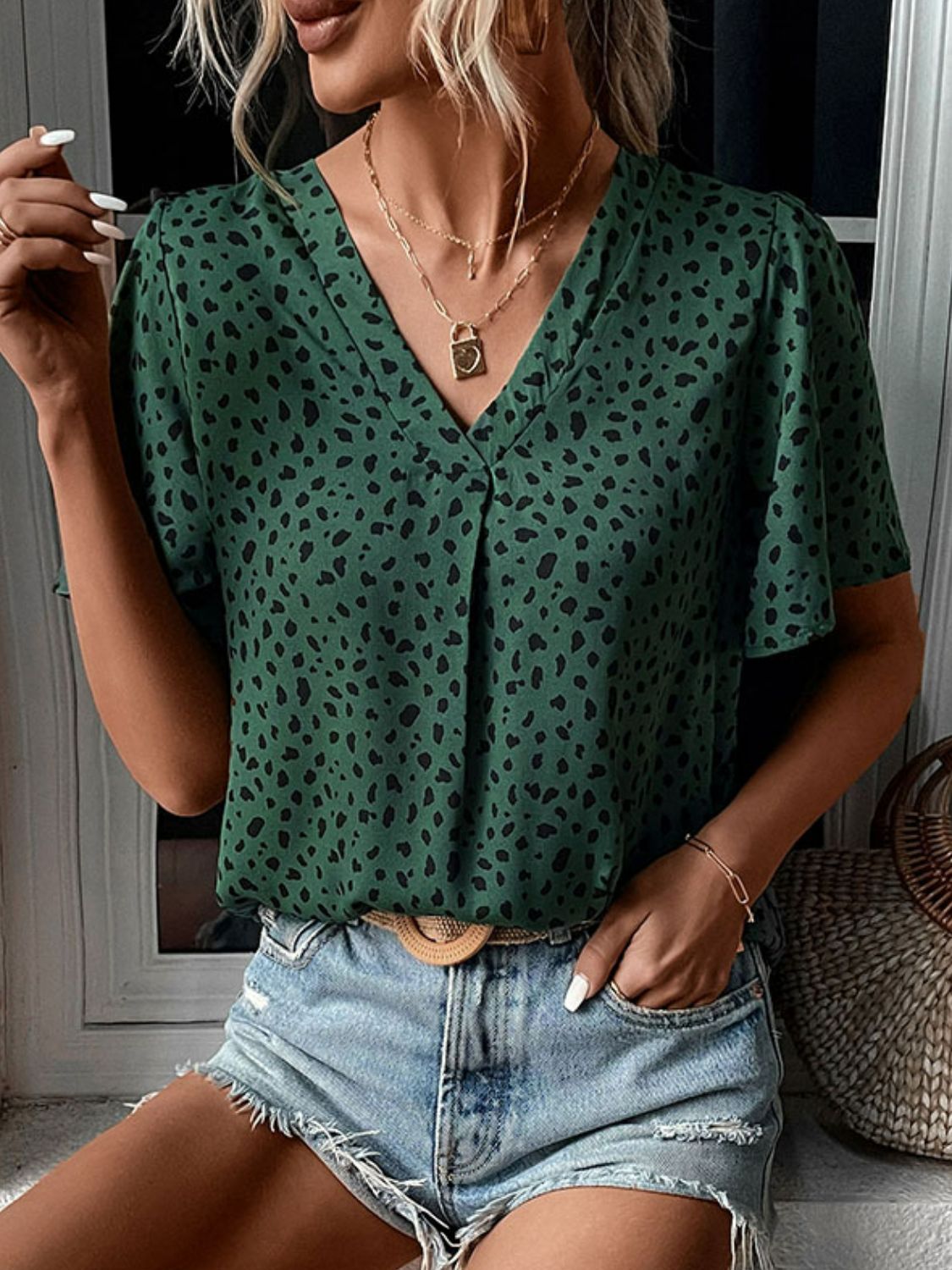 Emerald leopard print V-neck blouse with short flutter sleeves.