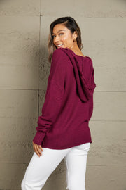 Burgundy knit hooded pullover sweater with fringe trim and textured sleeves.