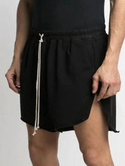Black lounge shorts with raw hem and high slit legs, featuring a drawstring waist.