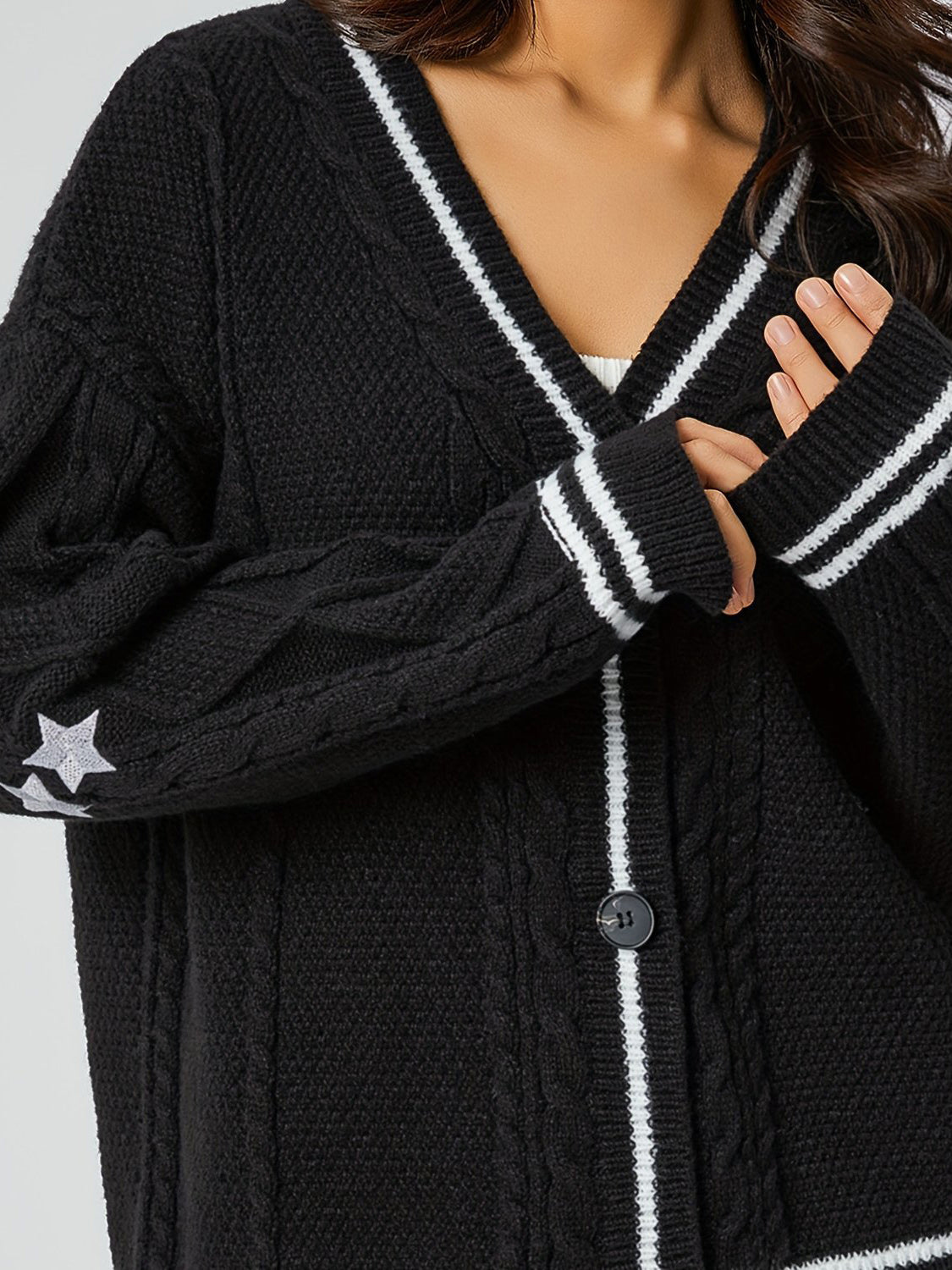Black cable knit cardigan with white stripe trim and star detail on sleeve.