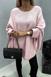 Blush pink knit sweater with relaxed fit and cape sleeves, featuring a wide neckline and textured knit pattern.