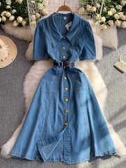 Light blue collared denim midi dress with short sleeves, gold buttons, and a belted waist.