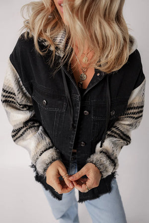 Black denim trucker jacket with plaid sleeves and hood, featuring frayed hem.