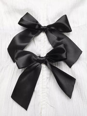 White maternity blouse with two black satin bow accents and cap sleeves.