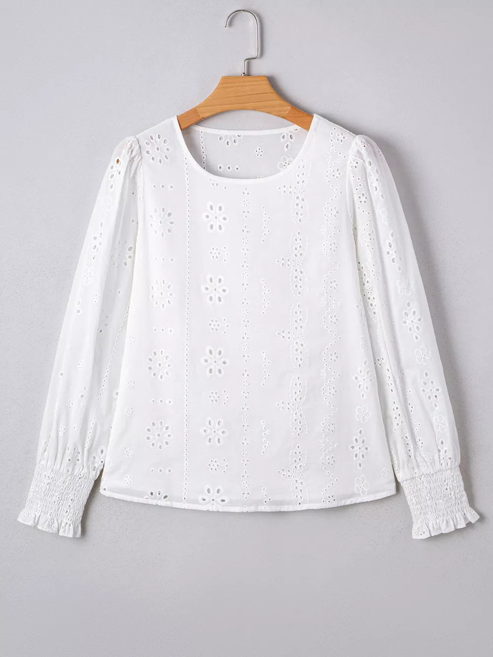 White cotton blouse with eyelet embroidery, ruffled cuffs, and puff sleeves.