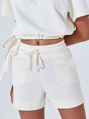 Cream drawstring pocket shorts with elastic waistband and cuffed hem