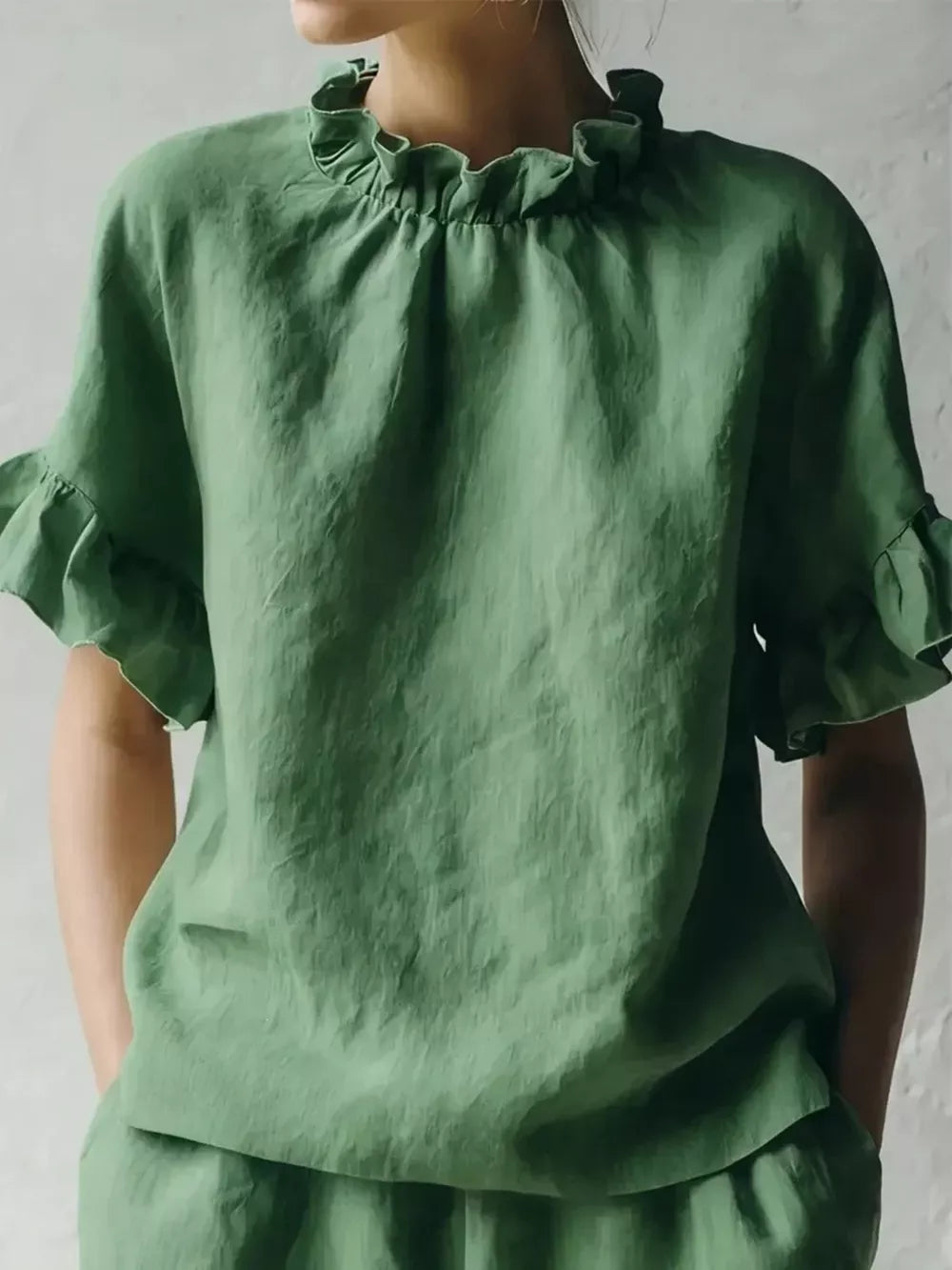 Emerald green shirt with ruffled neckline and half sleeves.