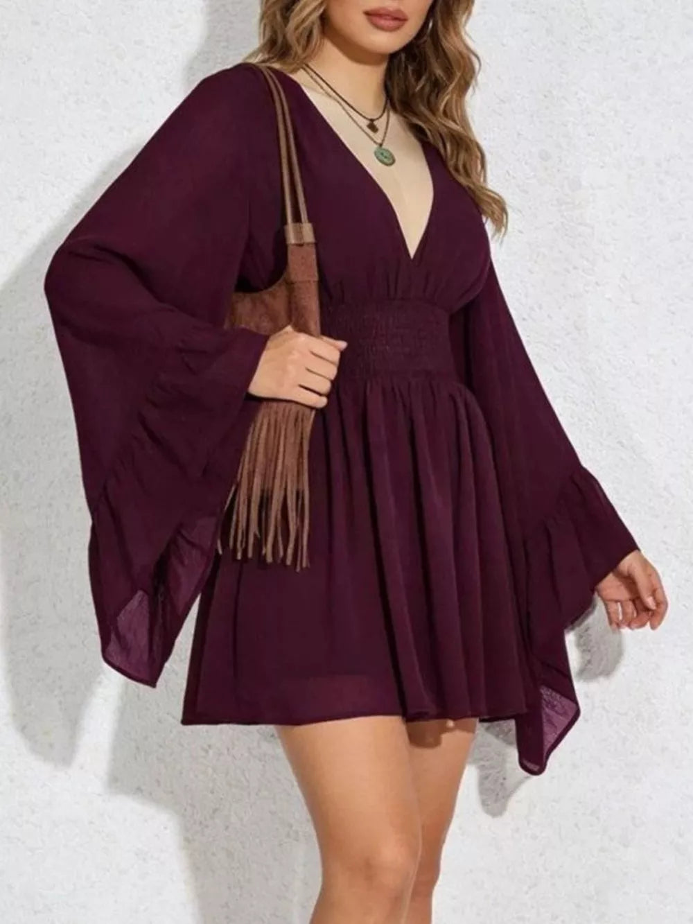 Burgundy a-line mini dress with plunging V-neck, bishop sleeves, and smocked waist.