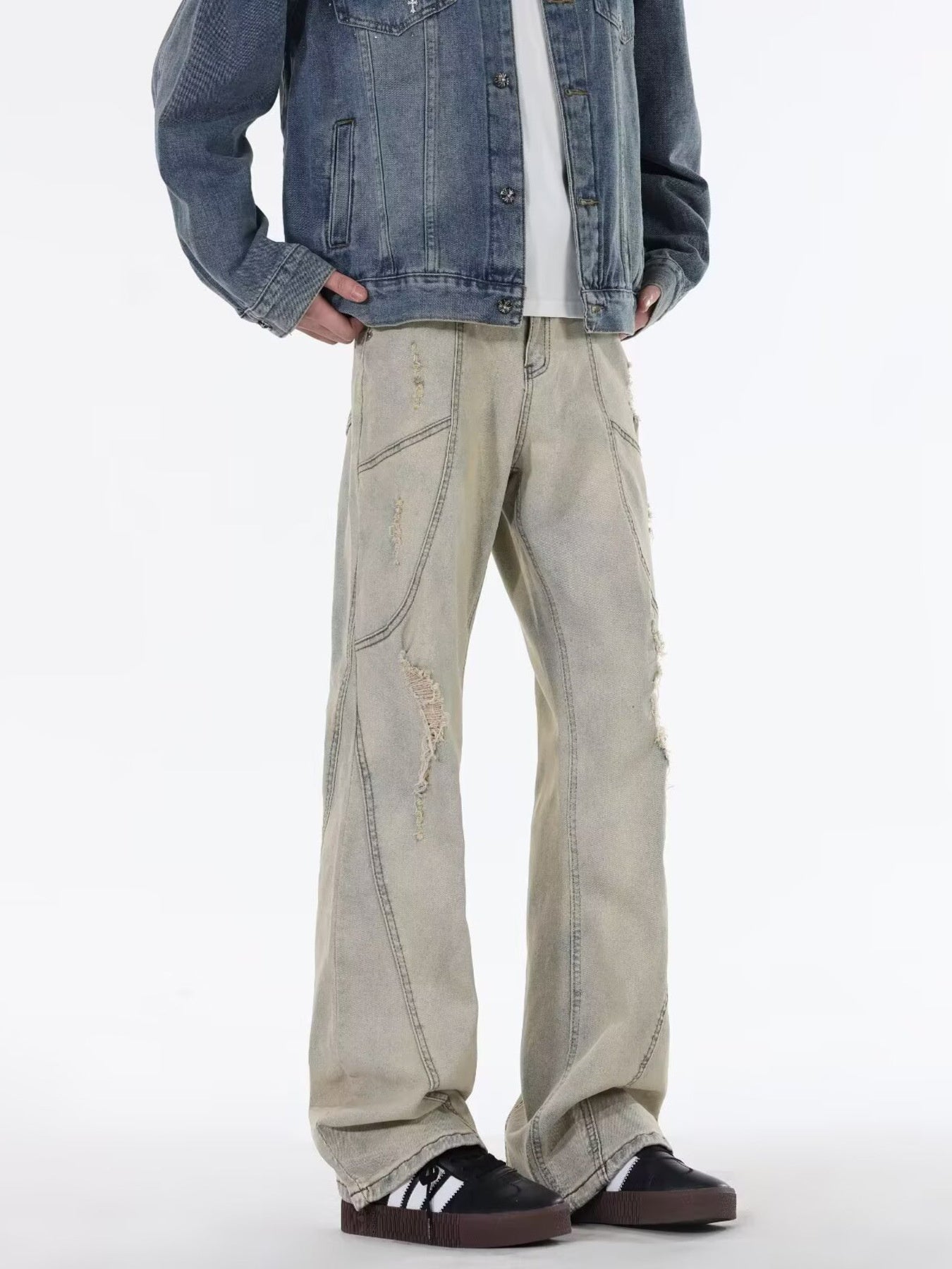 Men's beige wide leg jeans with distressed details and paneling.