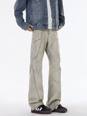 Men's beige wide leg jeans with distressed details and paneling.