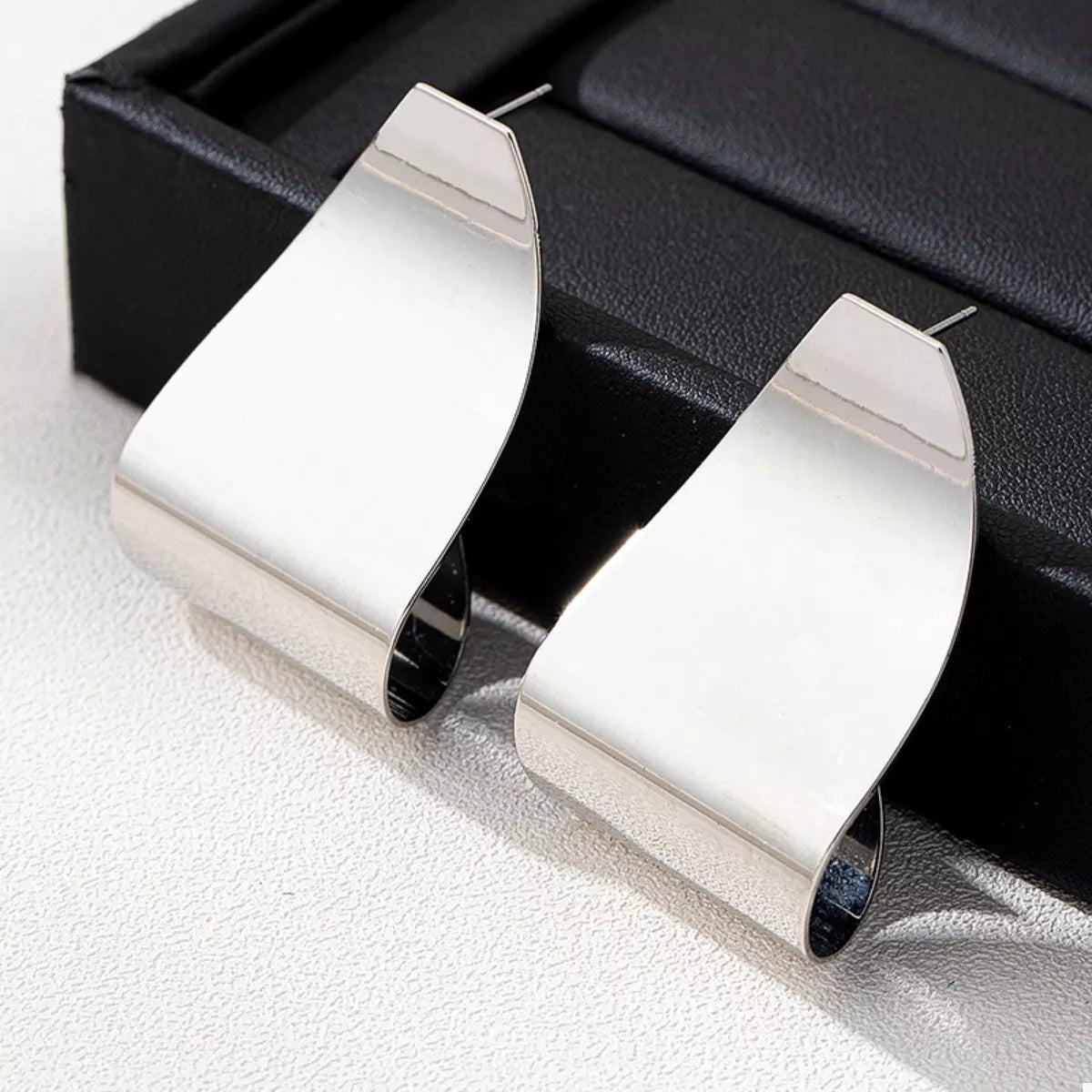 Silver alloy geometric earrings with a bold, curved design.