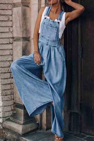Distressed denim palazzo dungaree jumpsuit in light wash with wide legs and front bib pocket.