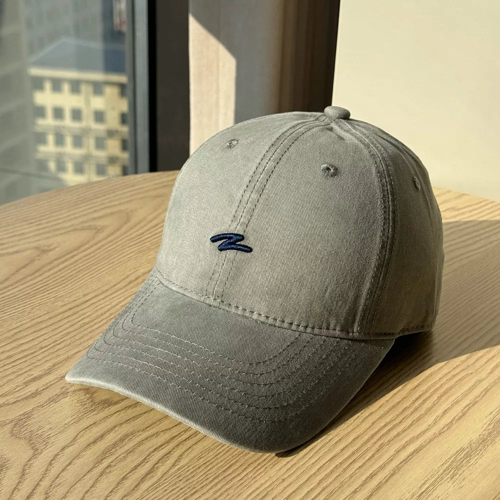 Distressed dark gray cotton baseball hat with curved brim and embroidered logo.
