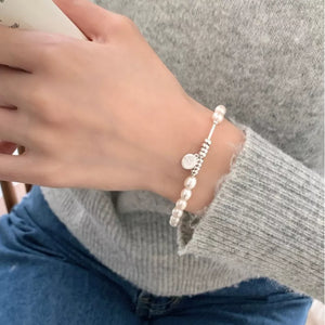 Delicate freshwater pearl and silver bracelet with charm detail