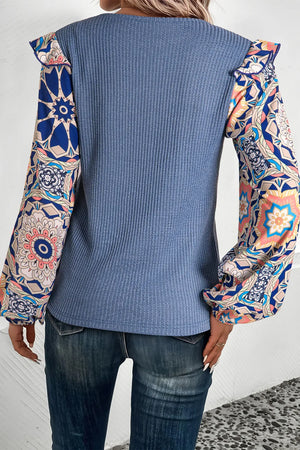 Dusty blue knit top with ruffled printed sleeves and a textured bodice.