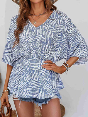 Light blue and white abstract print cinched waist blouse with V-neck and short sleeves.
