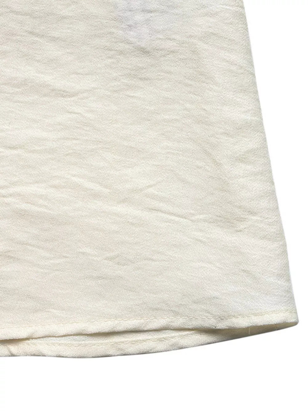 Beige maxi dress hem detail with textured fabric and subtle crinkles.