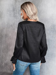 Black satin blouse with subtle animal print and ruffle cuffs