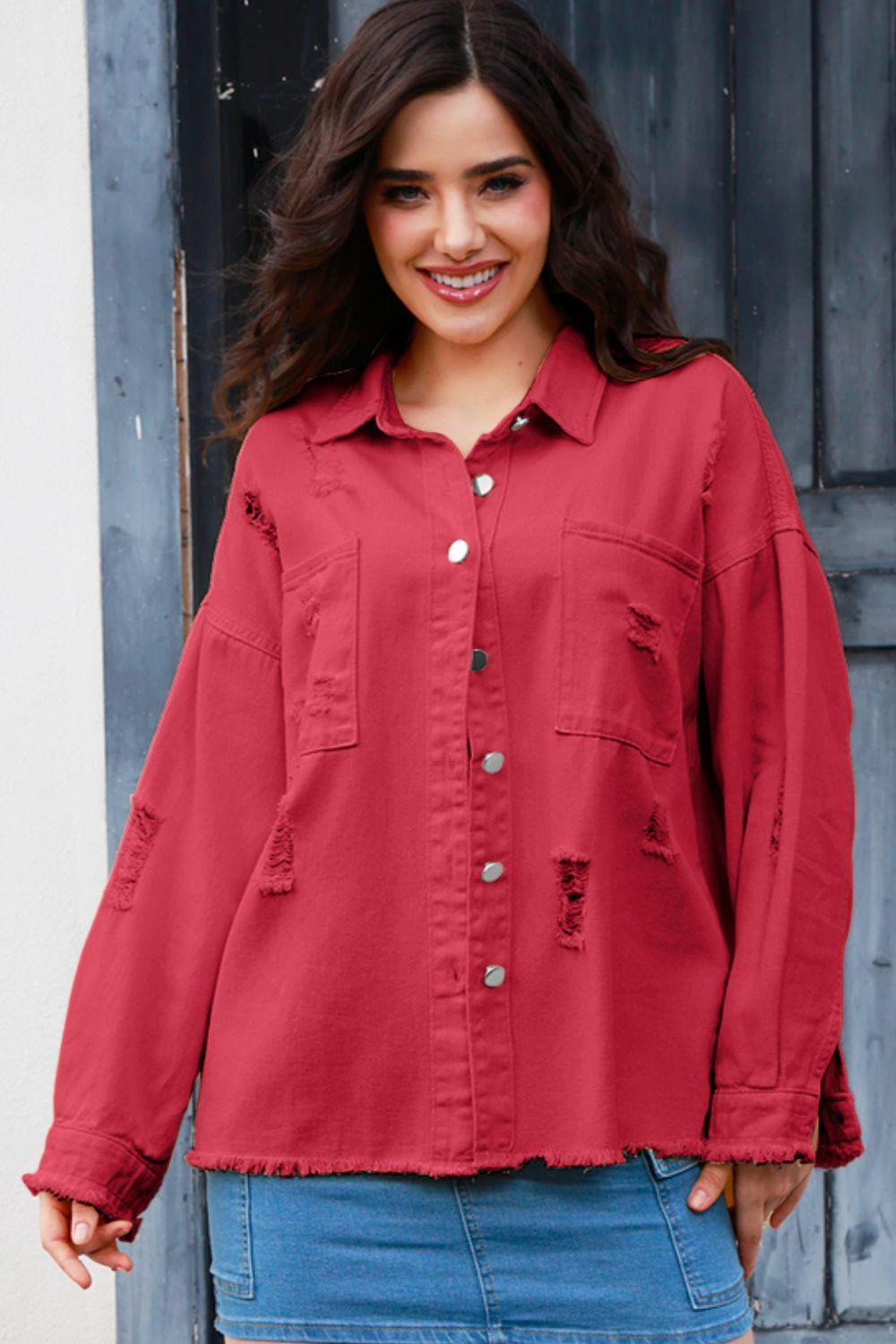 Distressed crimson denim overshirt with frayed details and silver buttons, styled casually.