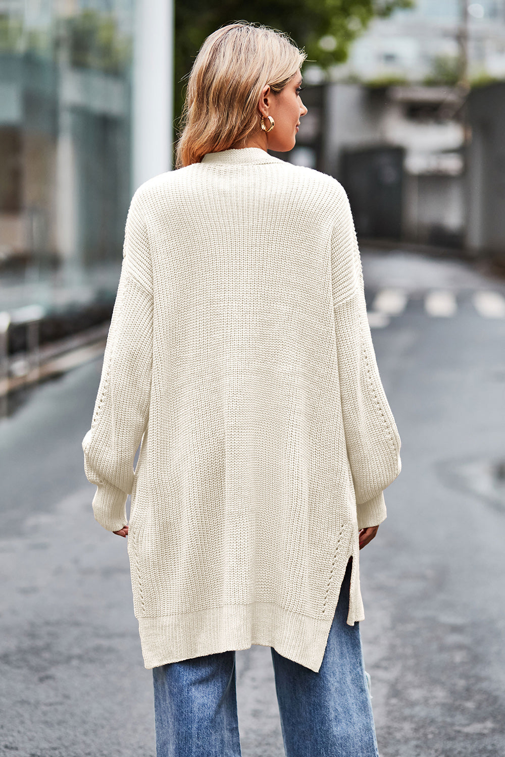 Cream open-knit longline cardigan with side slits and textured sleeves.