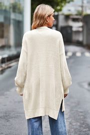 Cream open-knit longline cardigan with side slits and textured sleeves.