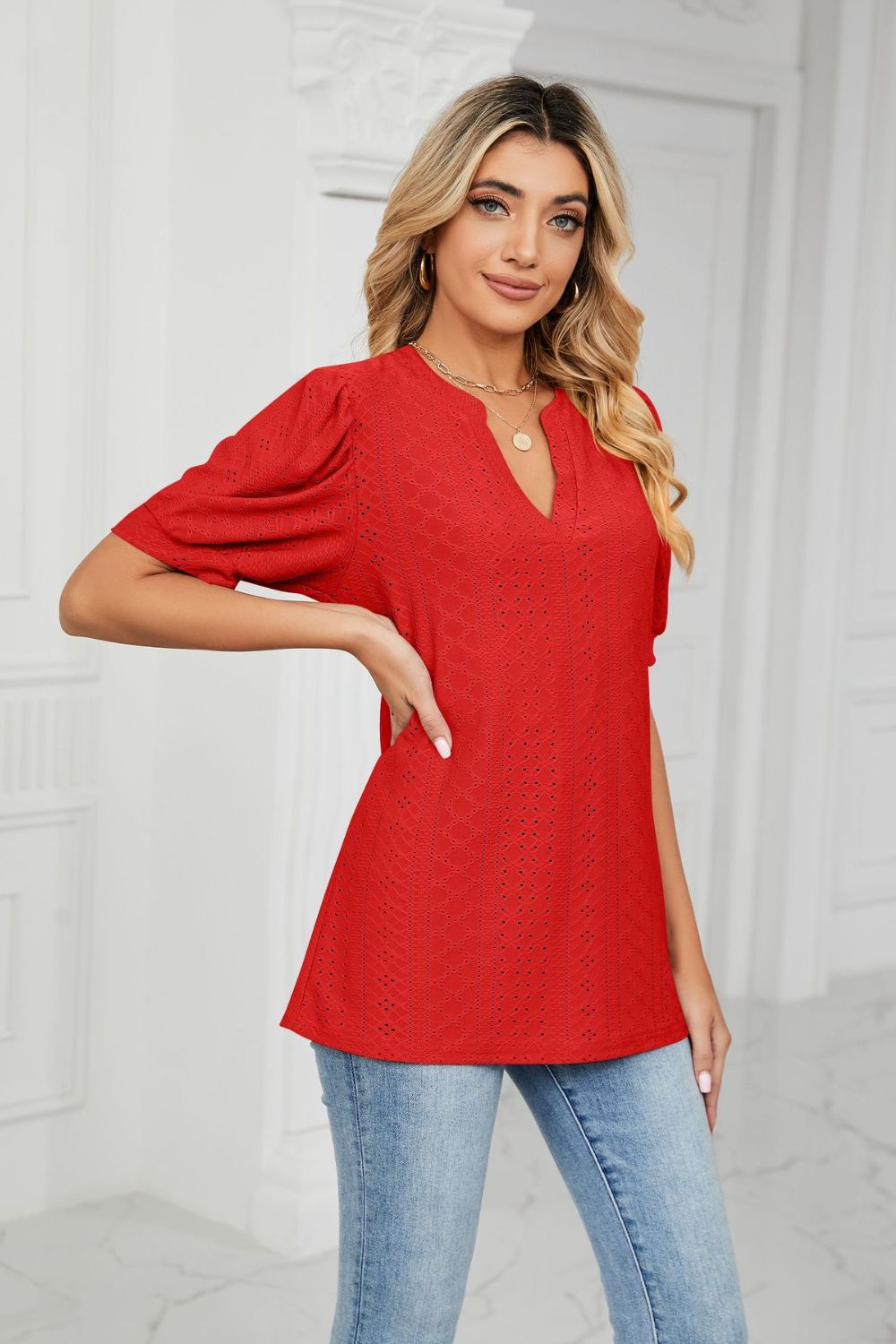 Red perforated puff sleeve blouse with keyhole neckline and textured pattern.