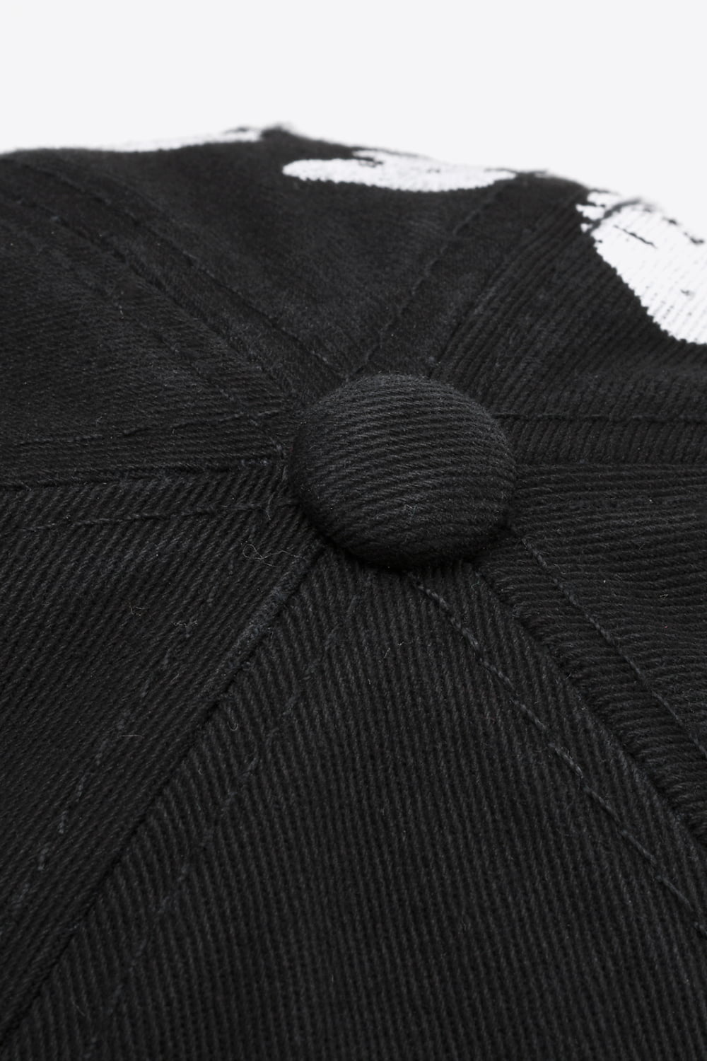 Black baseball cap with white graffiti detail and button top.