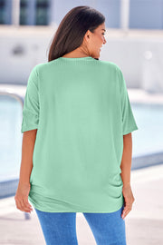 Light Green ribbed batwing cardigan with short sleeves and a draped front, worn with jeans.