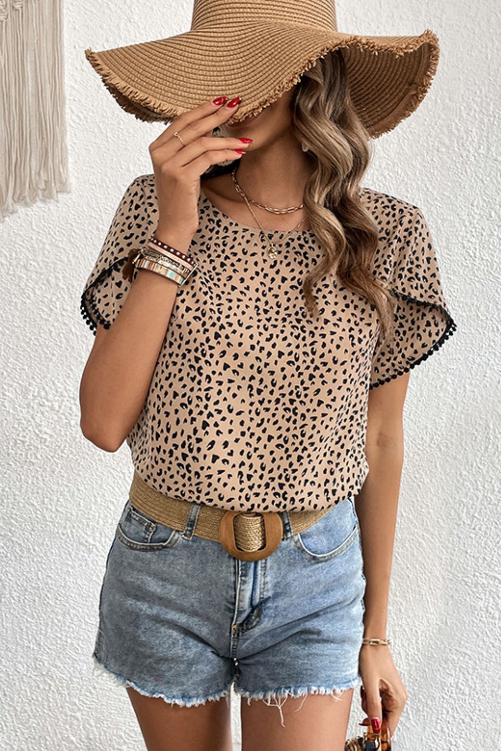 Leopard print blouse with pom-trim flutter sleeves and a round neckline.
