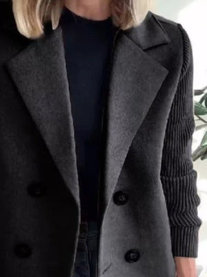 Double-breasted charcoal gray trench coat with ribbed knit sleeves and black buttons.