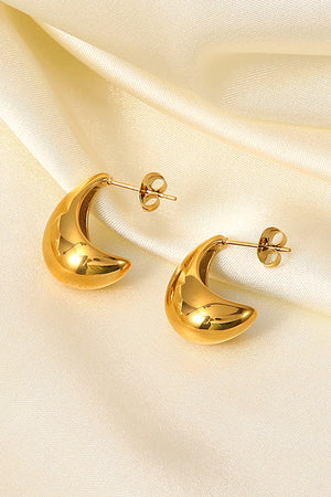 Gold sculpted crescent hoop earrings with post backs on a satin background.