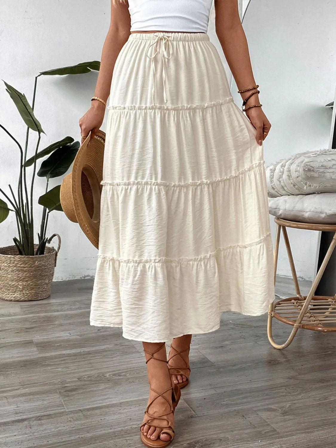 Cream tiered midi skirt with drawstring waist and textured fabric.