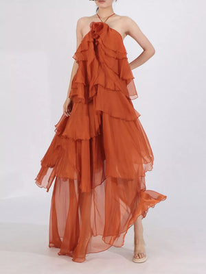Orange ruffle halter maxi dress with layered skirt and floral detail at neckline.