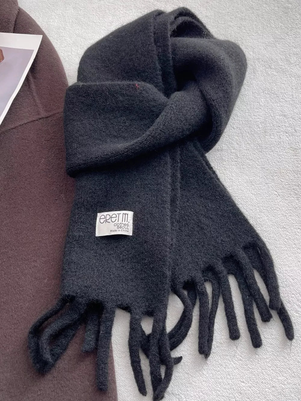 Plush fringe scarf in solid black with a cozy texture and fringed ends.