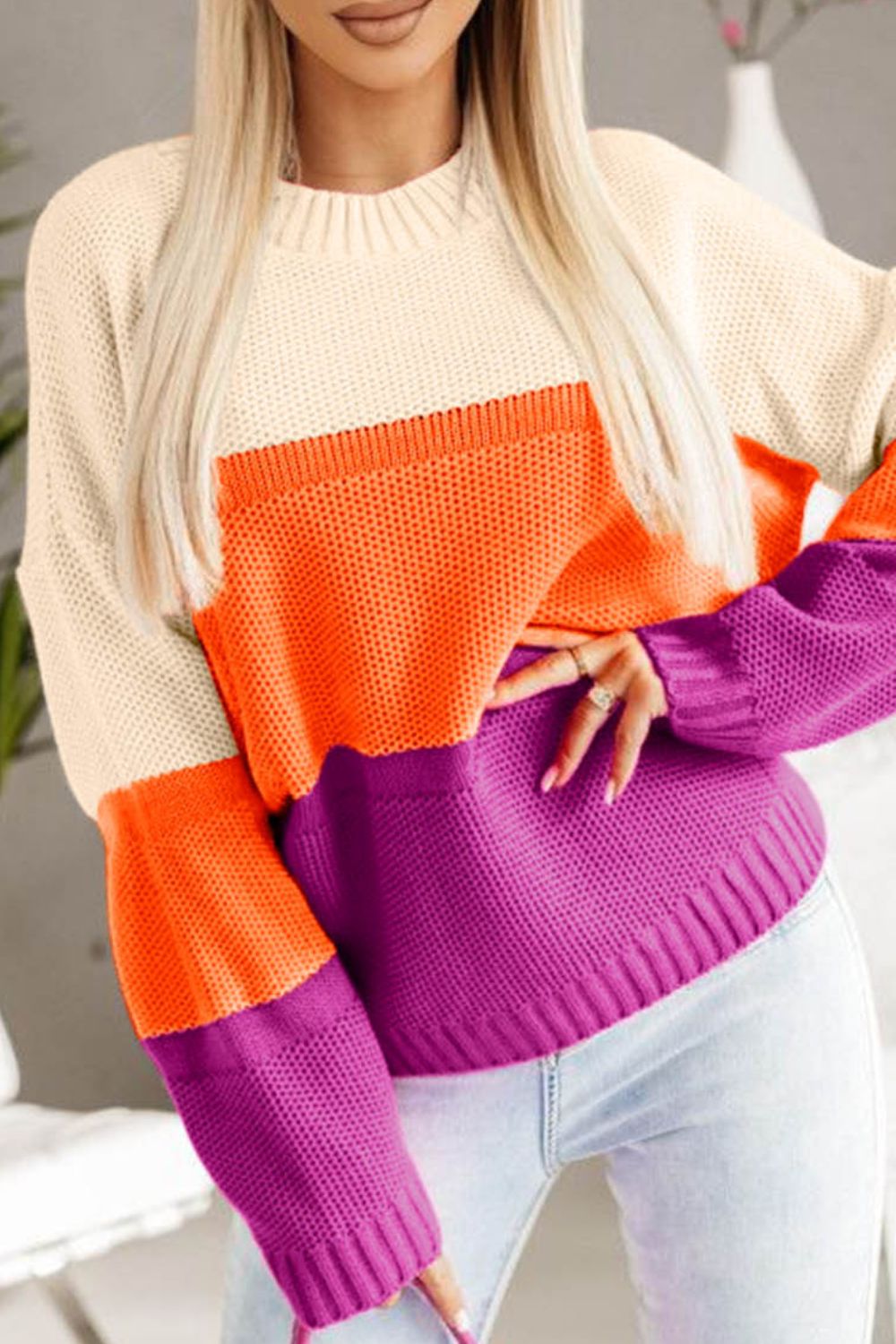 Colorblock ribbed knit pullover sweater with crew neck and long sleeves in cream, orange, and purple.