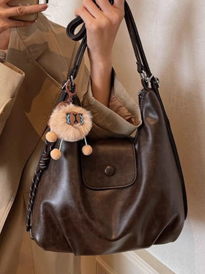 Slouchy coffee brown pu leather shoulder bag with flap pocket and fuzzy charm