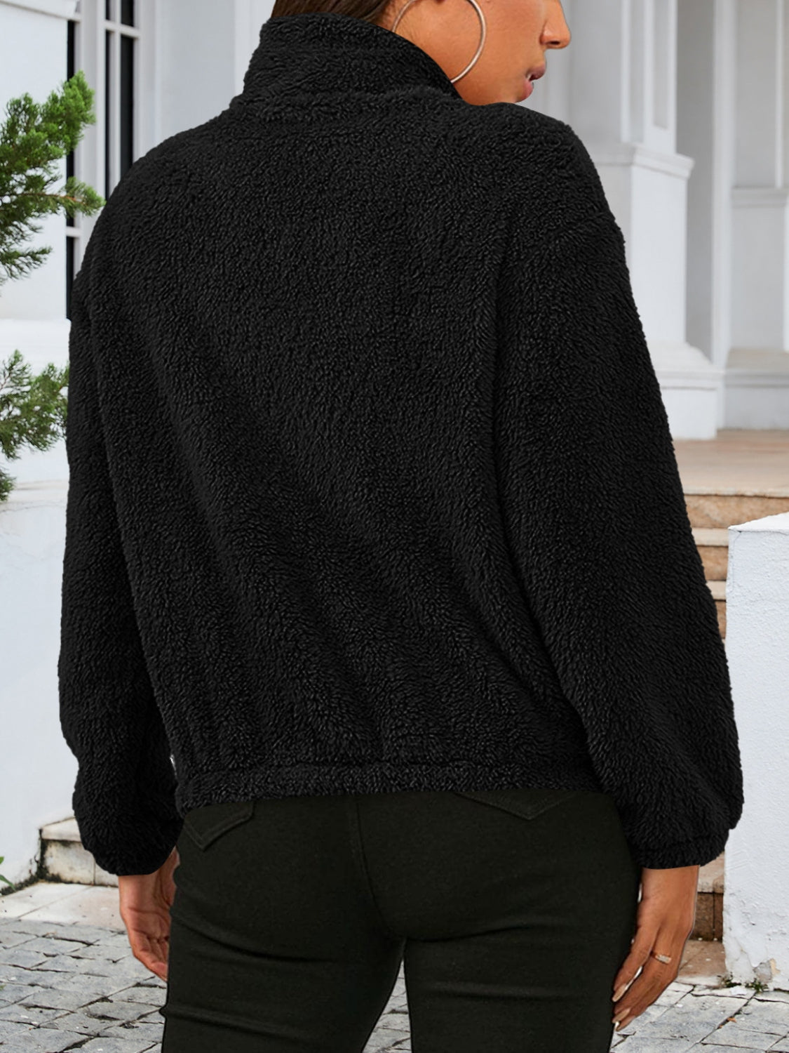 Black sherpa bomber jacket with a high collar and elastic cuffs.
