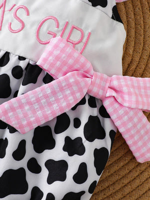 Baby one-piece with cow print, pink gingham bow, and embroidered text.