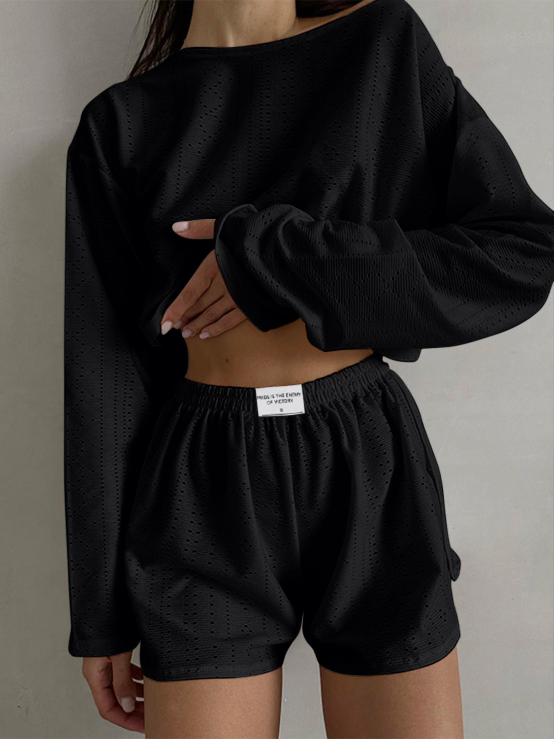 Black perforated crop top and shorts set with long sleeves and elastic waistband.
